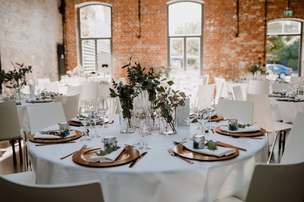 Ein Tisch einer gedeckten Hochzeitstafel ohne Personen in einer Halle